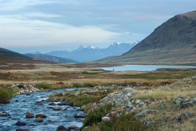 Scenic view of river and mountains against sky