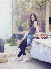 Full length portrait of young woman sitting outdoors