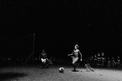 People playing soccer ball against star field at night