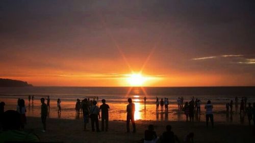 Silhouette of people on beach at sunset