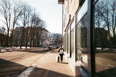 Woman walking on street amidst buildings in city
