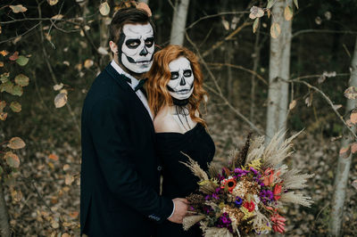 Portrait of woman wearing mask standing against trees