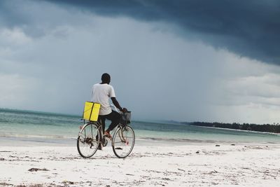 Rear view of man riding bicycle at beach
