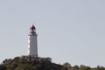 Low angle view of lighthouse by building against sky