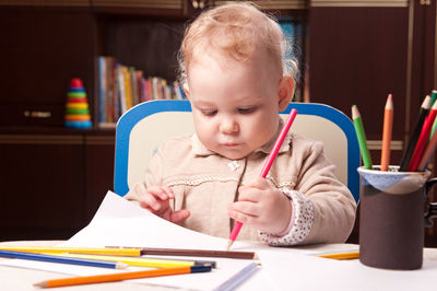 Cute girl holding pencil on table