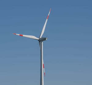 Low angle view of wind turbine against clear blue sky