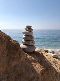 Stack of stones on beach against sky