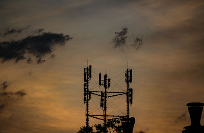 Low angle view of silhouette communications tower against sky during sunset