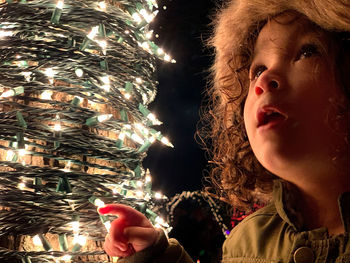 Portrait of girl with illuminated christmas tree
