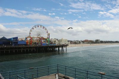 Ferris wheel by sea against sky