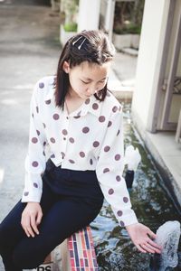 Girl sitting by water fountain outdoors