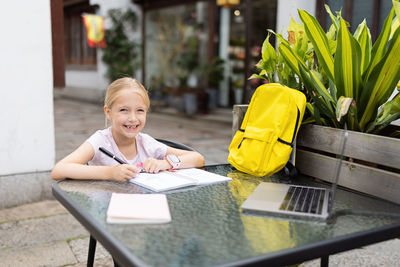 Happy caucasian kid has online lesson on laptop during coronavirus covid-19 pandemic and lockdown