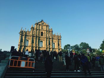 People at temple against clear blue sky