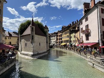 Buildings by river against sky