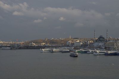Boats in sea against cloudy sky