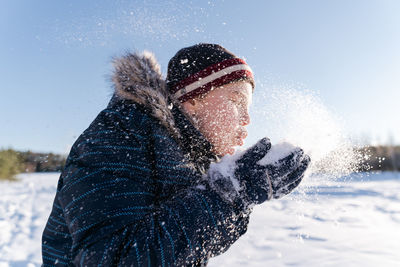 Close-up of boy blowing snow during winter