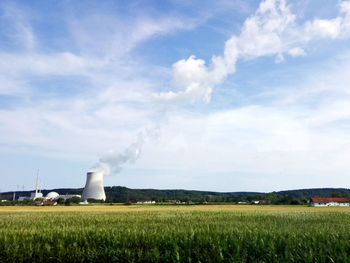 Smoke emitting from chimney on field against sky