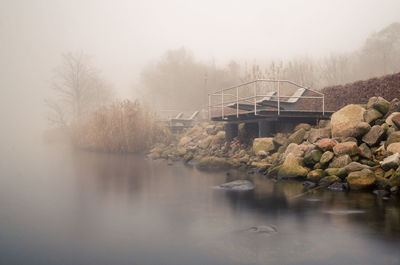 Scenic view of river against sky during foggy weather