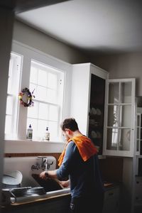 Man washing utensils in kitchen