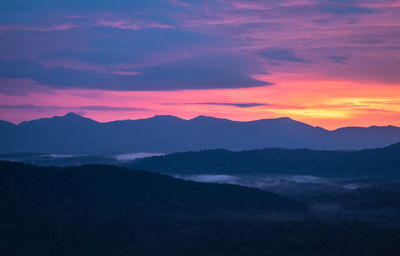 Mountains range misty shadow with dramatic colorful sunset sky at dusk from flat angle