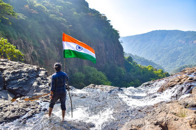 Rear view of man standing on rock with indian flag