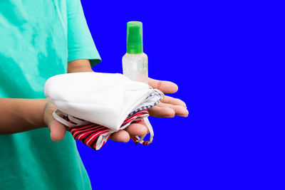 Midsection of woman holding umbrella against blue sky