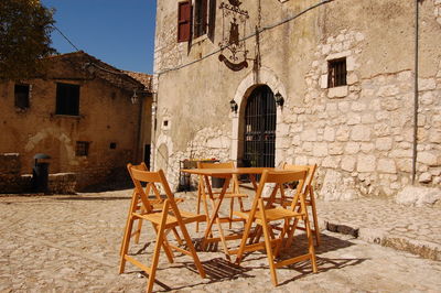 Empty chairs and tables at sidewalk cafe by building