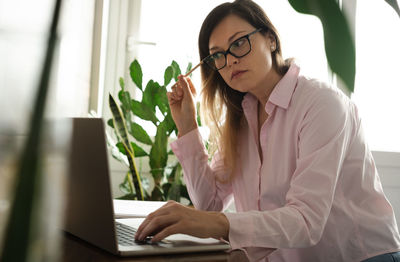 Portrait of young woman using laptop at table