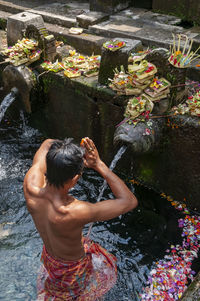 Rear view of shirtless man standing in water