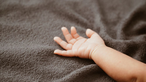 Close-up of baby hand on bed