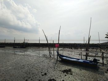 Fishing boat on beach against sky