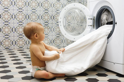 Portrait of cute baby girl sitting on bed at home