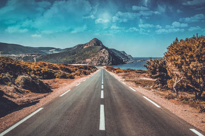 Road by mountains against sky