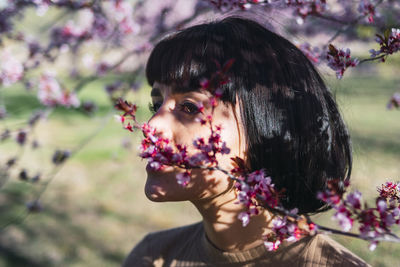 Portrait of woman with pink flowers against blurred background