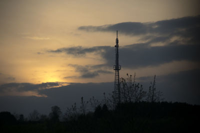 Low angle view of silhouette communications tower against sky during sunset