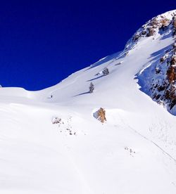 Scenic view of snow covered mountains against clear blue sky