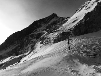 Cross on snowcapped mountain against sky