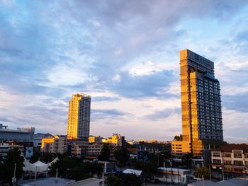 Buildings in city against cloudy sky