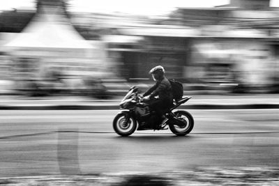 Blurred motion of man riding motor scooter on street