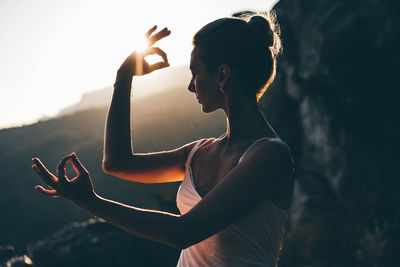 Rear view of woman with arms raised standing against sky