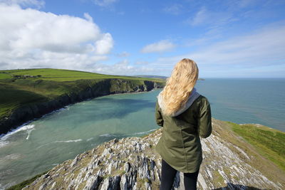 Rear view of woman standing by sea against sky