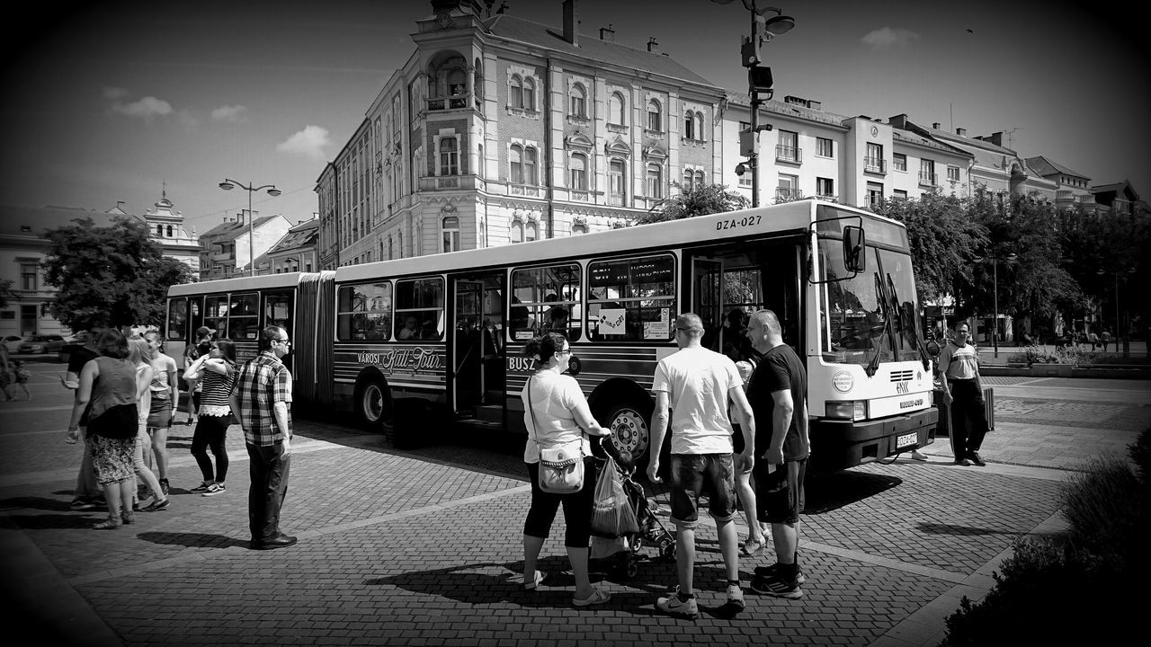 PEOPLE WALKING ON CITY STREET BY BUILDINGS