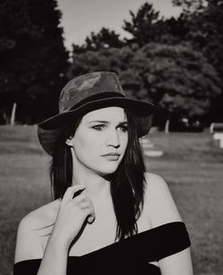 Young woman wearing hat looking away while standing outdoors