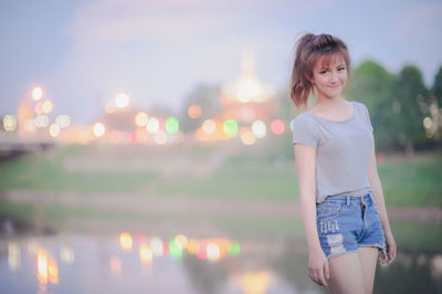 Portrait of happy woman standing against illuminated temple