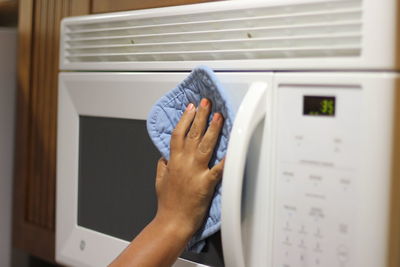Cropped hand cleaning oven in kitchen at home