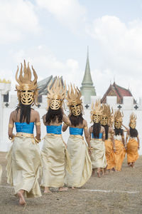 Rear view of women wearing traditional costumes while walking in row outside temple