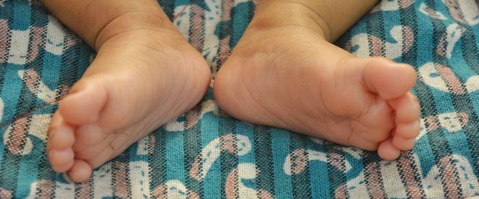 Low section of baby feet on bed