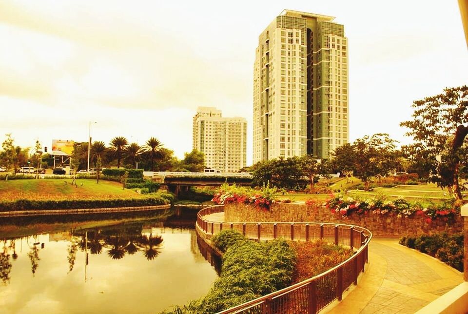 architecture, building exterior, built structure, tree, city, sky, water, reflection, incidental people, pond, growth, park - man made space, river, skyscraper, fountain, city life, tall - high, tower, outdoors, cloud - sky