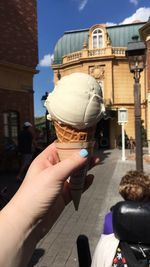 Cropped image of hand holding ice cream in city