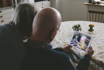 Couple having video chat with baby grandson on tablet